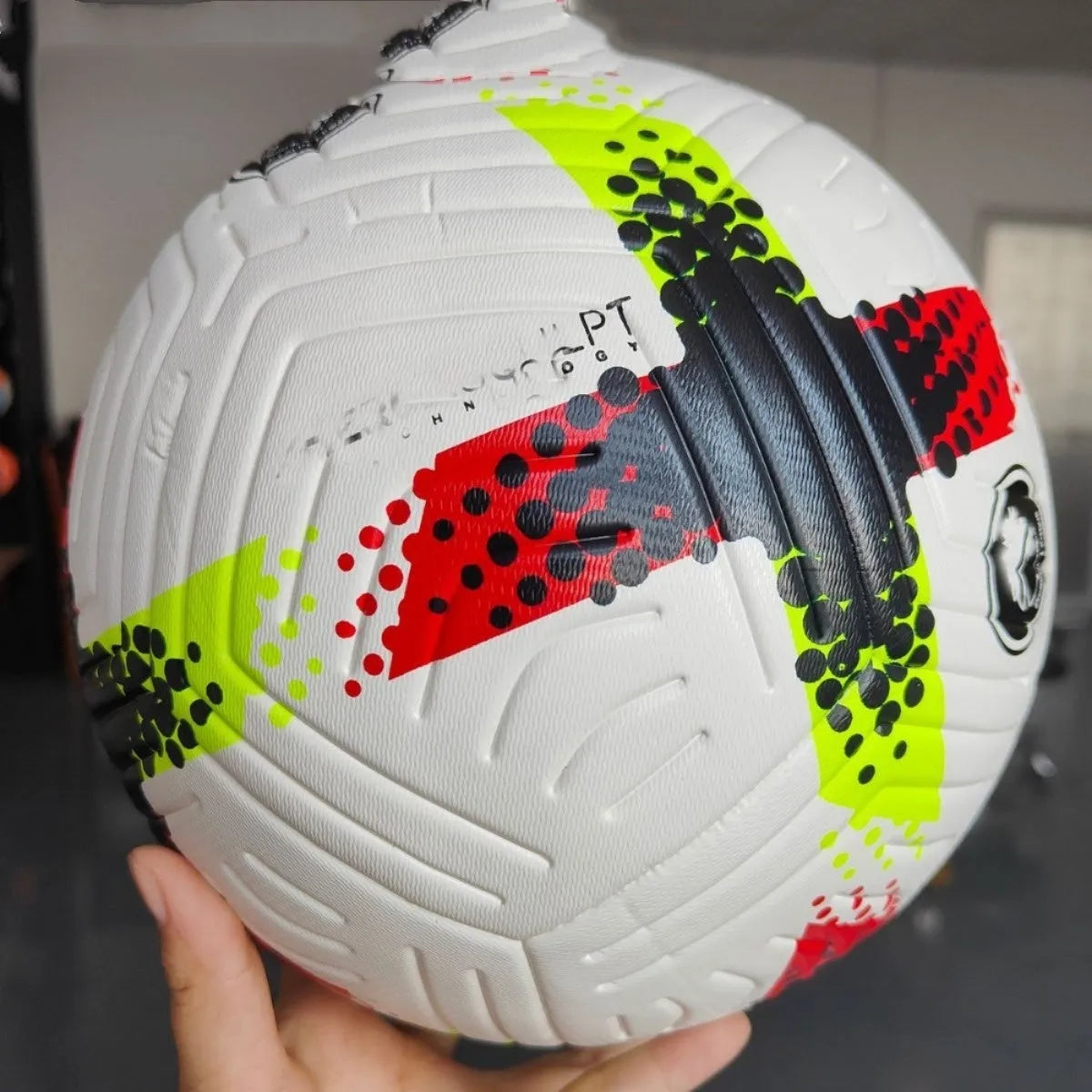 Fluorescent green Size 5 football with seamless patch construction on a green pitch.