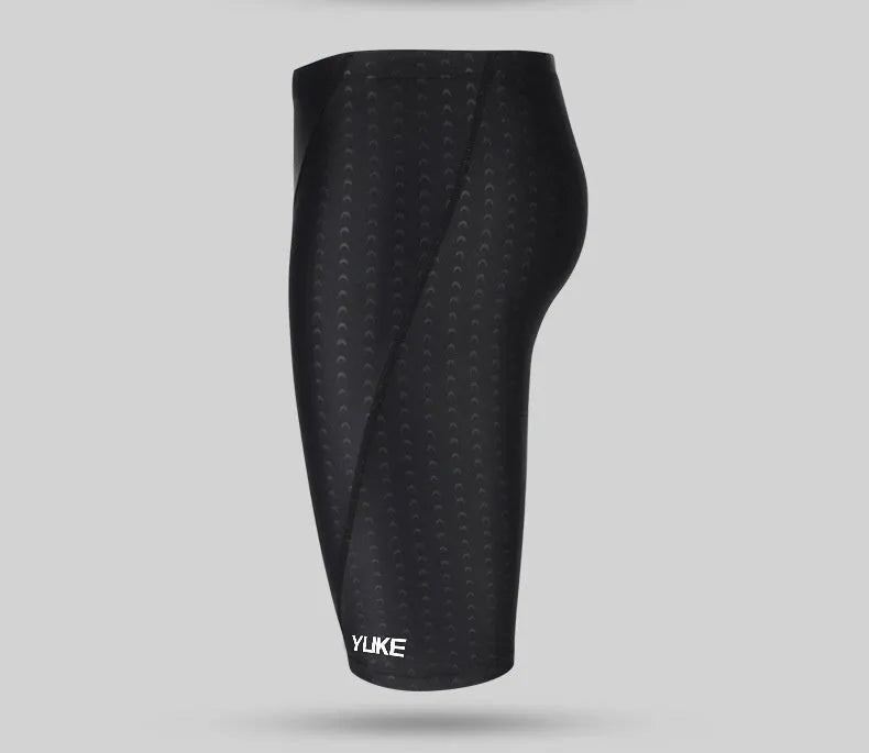 Men's black swimming trunks, goggles, and cap set laid out with ear plugs and carry bag