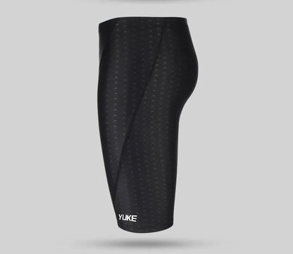 Men's black swimming trunks, goggles, and cap set laid out with ear plugs and carry bag