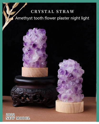 Miniature amethyst crystal tooth flower night light glowing with warm light on a wooden surface.