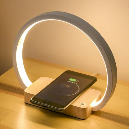 White wireless charging table lamp with metal shade and button switch on wooden surface