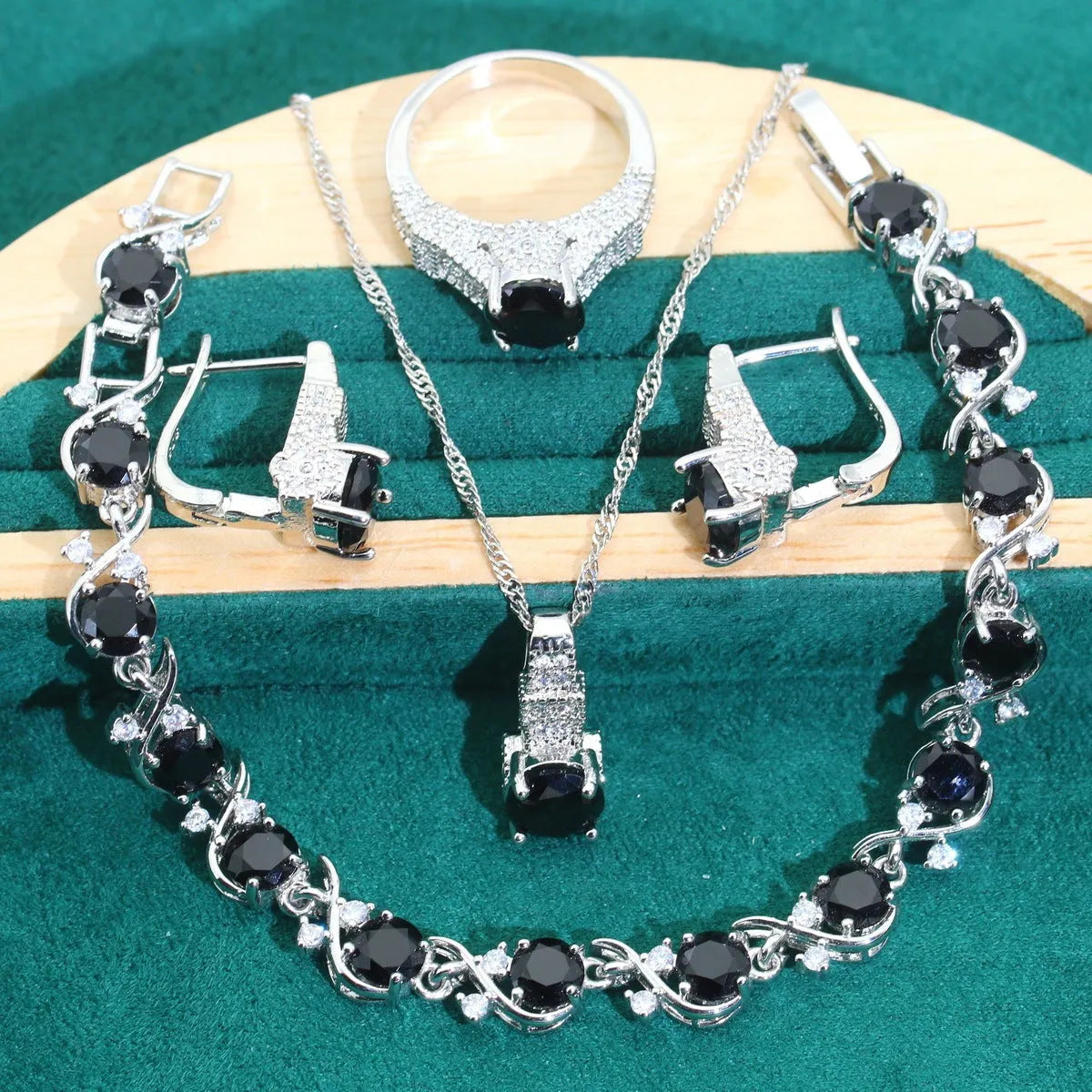 Four-piece bridal jewellery set with zircon pendants on a water wave chain, showing necklace, bracelet, earrings and ring.