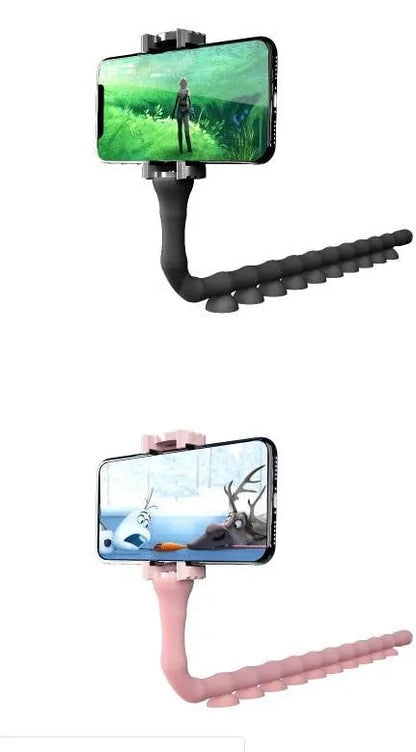 Black flexible gooseneck phone holder with suction cup mounted on a desk, holding a mobile phone at an angle.
