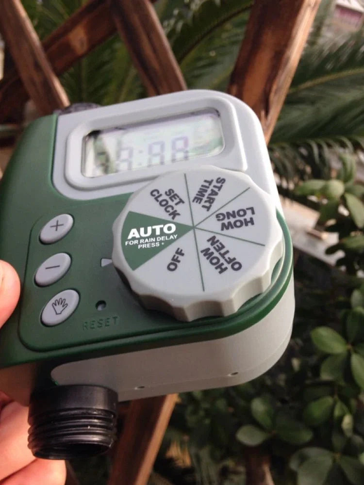 Green garden irrigation controller with LCD display and rotating dial for programming watering schedules