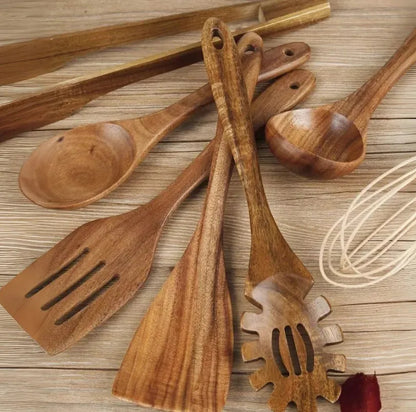 Set of seven light brown wooden cooking utensils including spoons, spatula, and turner on a kitchen counter.