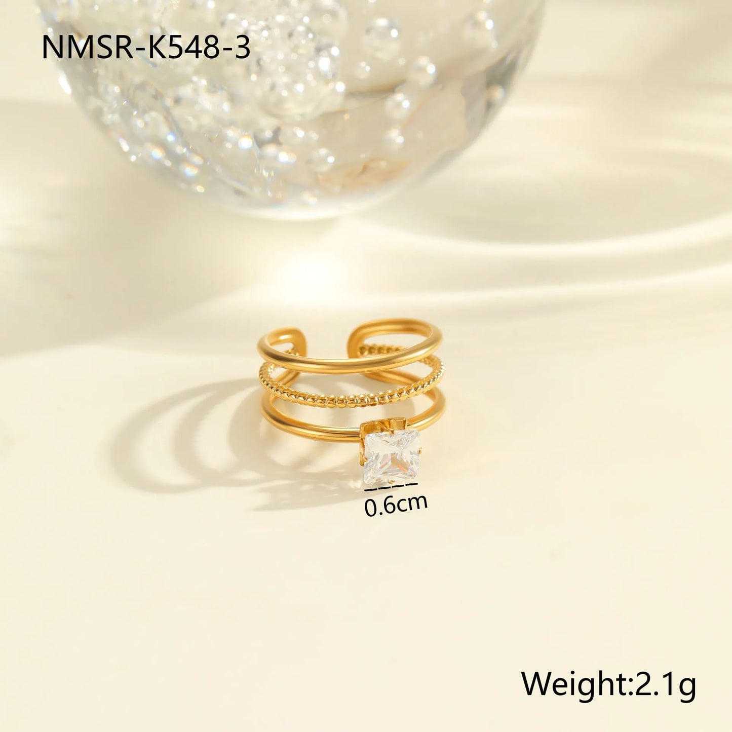 Gold electroplated stainless steel open mouth ring with geometric shapes and zircon inlay on a heart drop.