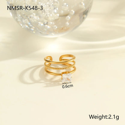 Gold electroplated stainless steel open mouth ring with geometric shapes and zircon inlay on a heart drop.