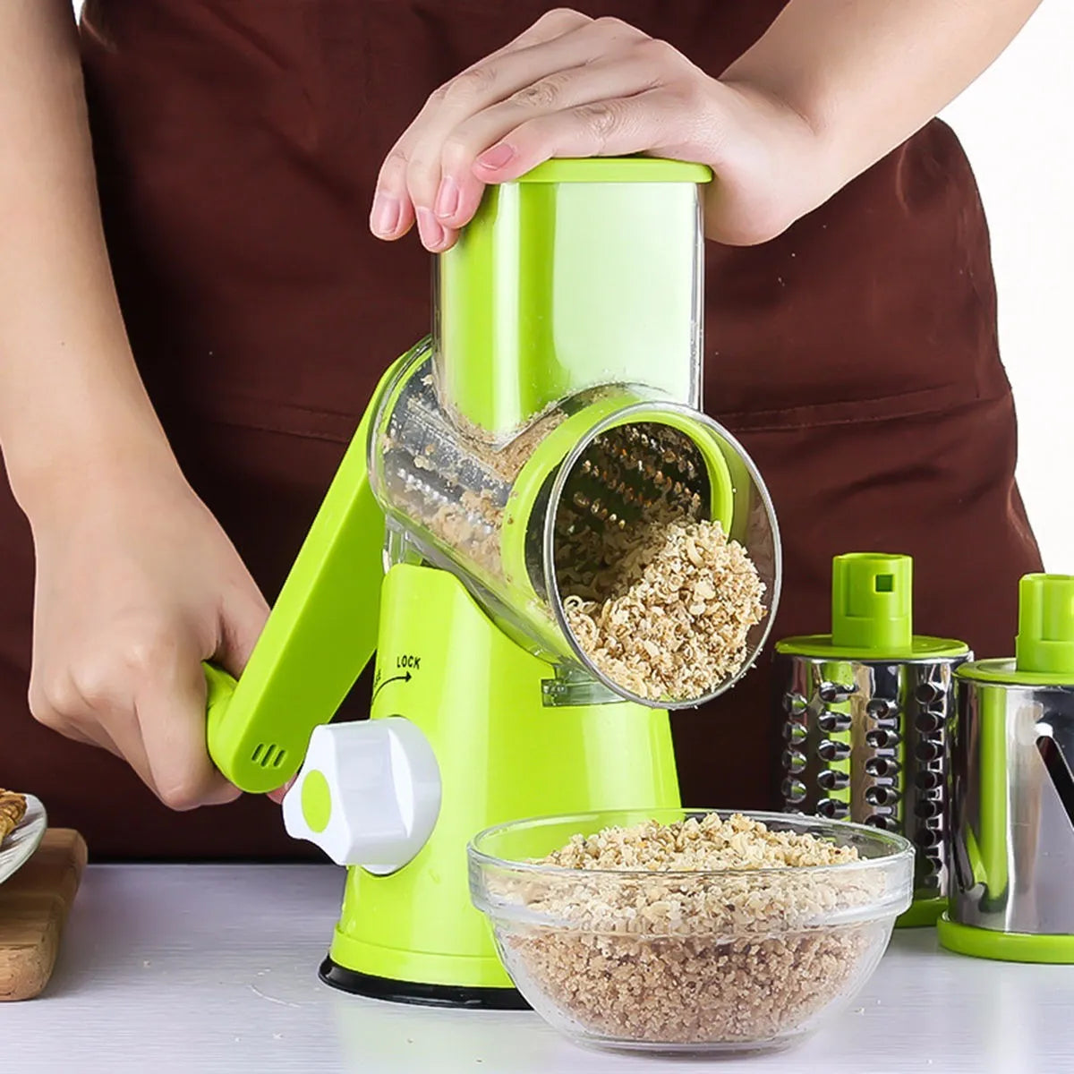 Round mandoline vegetable slicer with three stainless steel blades and a rubber suction base, in blue green colour.