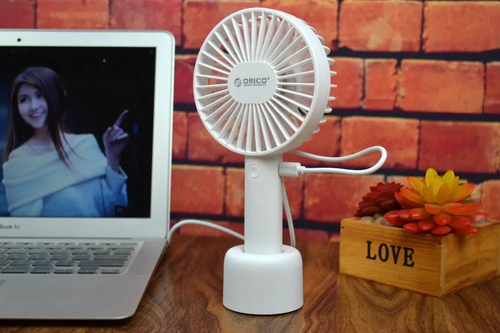 White ORICO FH1 portable USB desk fan with rechargeable battery on a wooden desk