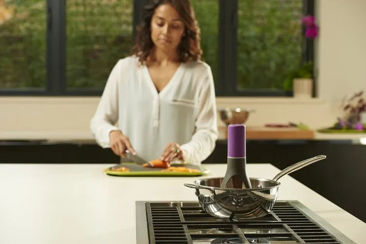 Uutensil Stirr automatic electric kitchen mixer device in green, shown next to a saucepan.