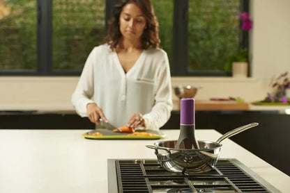 Uutensil Stirr automatic electric kitchen mixer device in green, shown next to a saucepan.