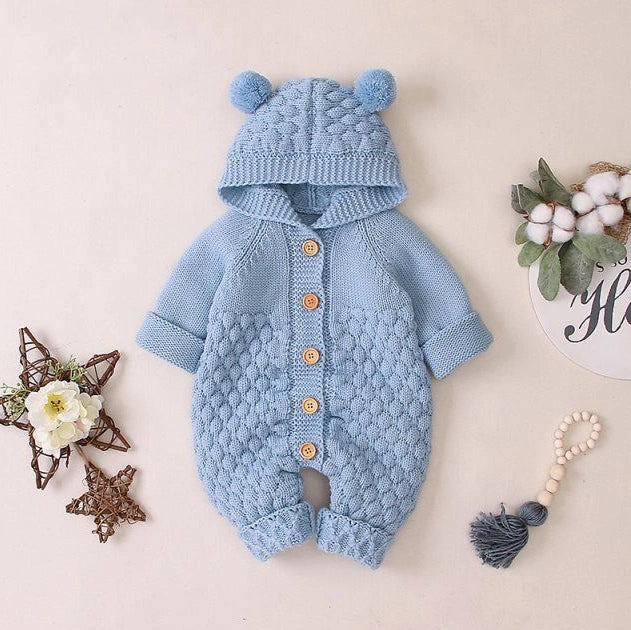 Baby wearing light blue knitted romper with hood and sleeveless design, single-breasted closure visible