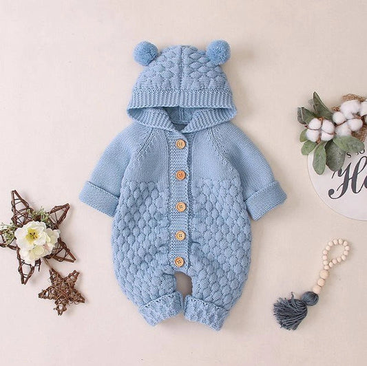 Baby wearing light blue knitted romper with hood and sleeveless design, single-breasted closure visible