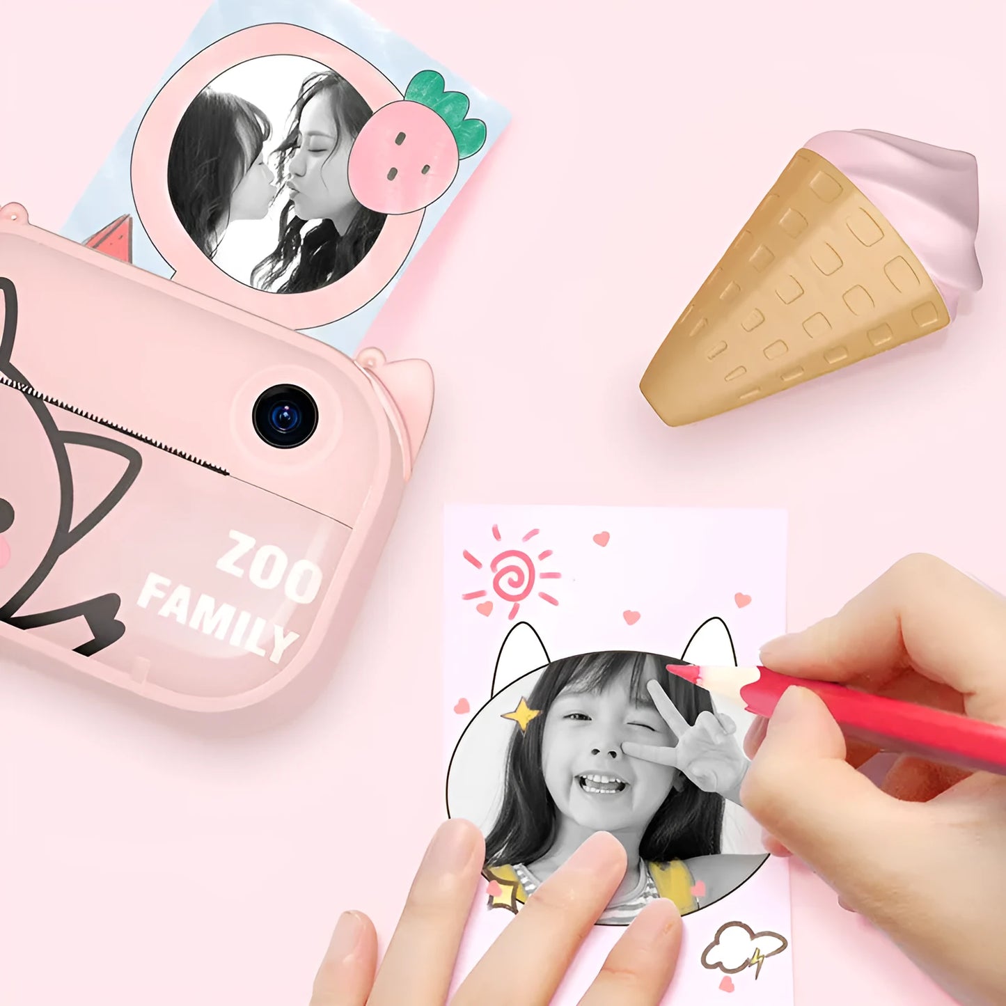 Pink instant print digital camera with LCD screen on a table next to printed photos and accessories.