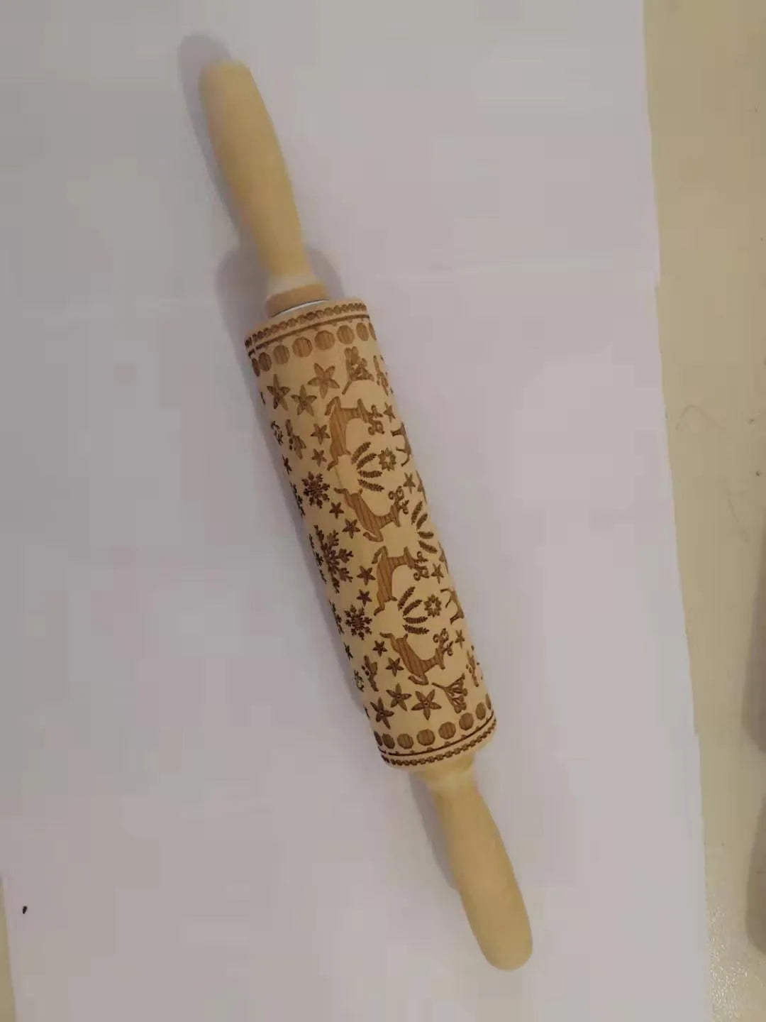 Wooden rolling pin with engraved Christmas patterns including reindeer and snowflakes on a 45cm long barrel.