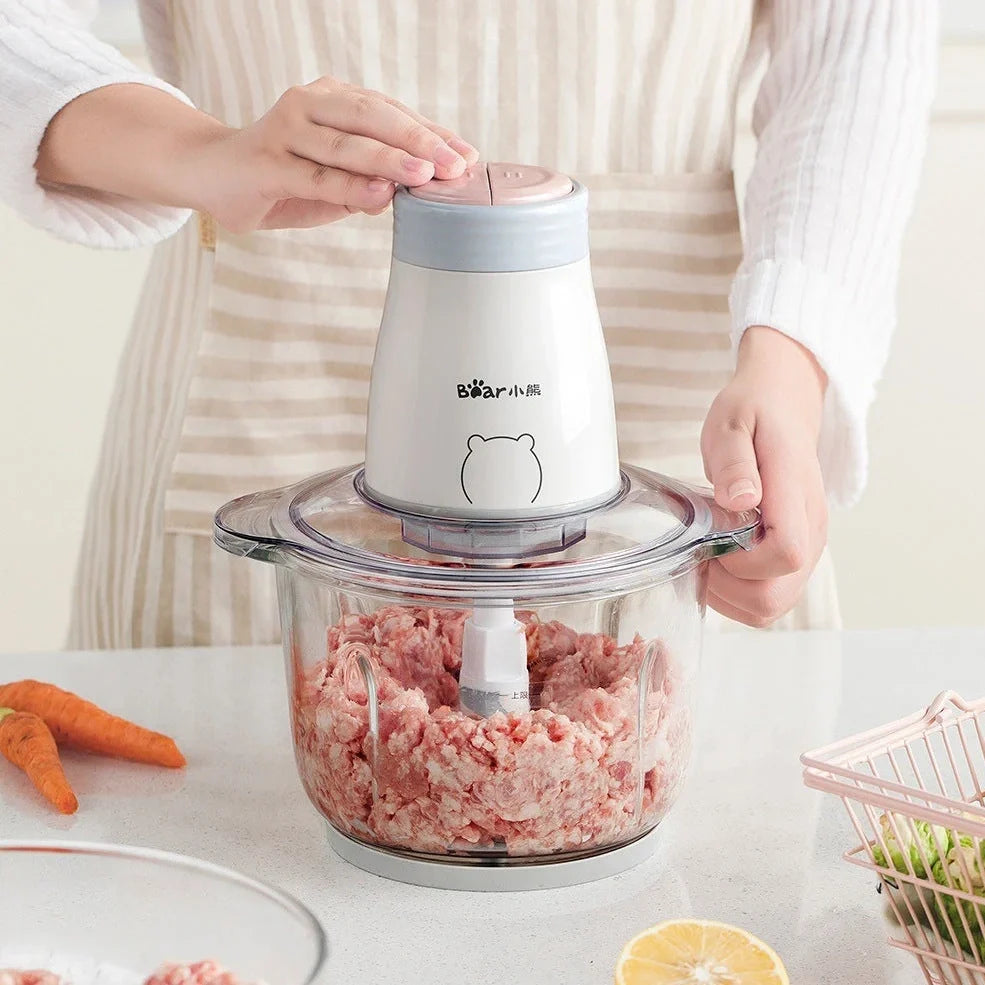 Household electric vegetable chopper blender with glass bowl and stainless steel blade on kitchen counter