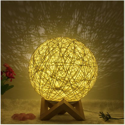 Spherical hand-knitted rattan table lamp with remote control on a wooden desk