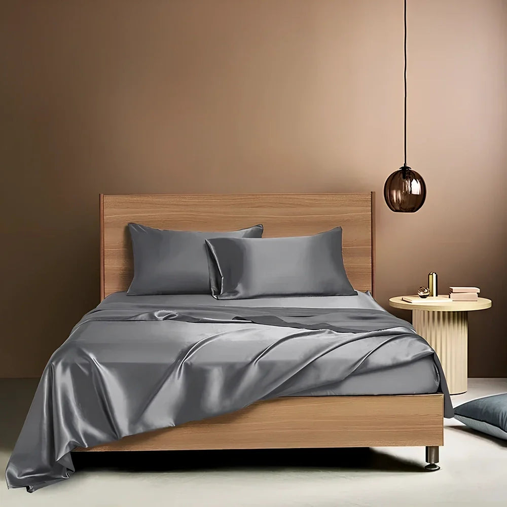 Navy blue floral pattern silk bedding set with quilt cover, fitted sheet, and two pillowcases on bed