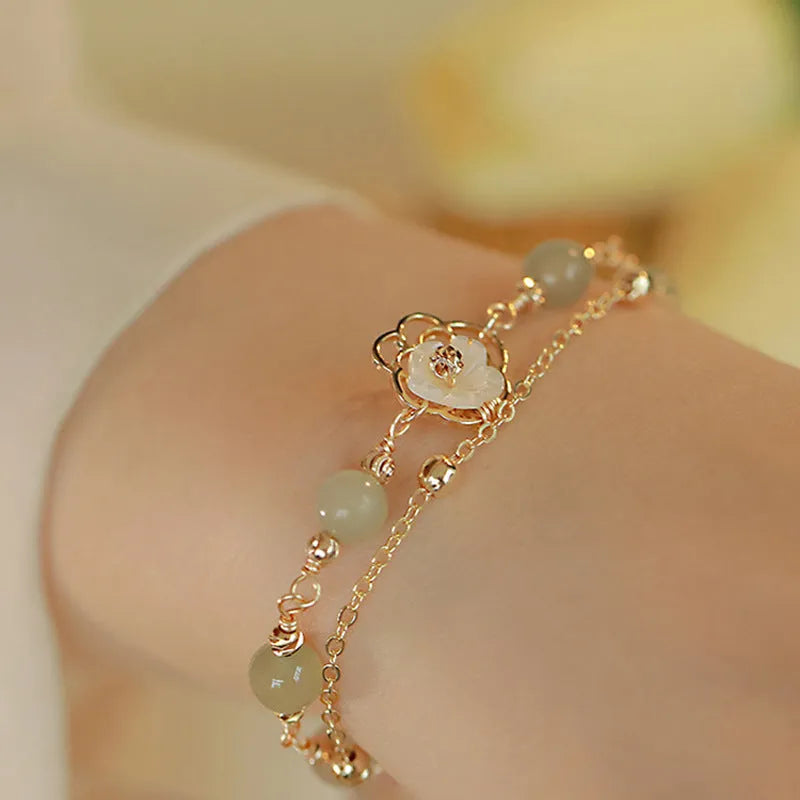 Women's shell flower butterfly bracelet in yellow gold with geometric design and hetian jade style charm.