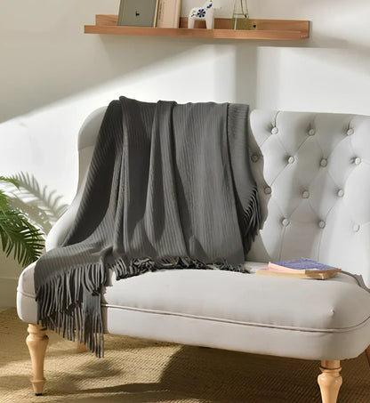 130x150cm knitted acrylic blanket with 10cm fringe detailing in beige colour draped over sofa