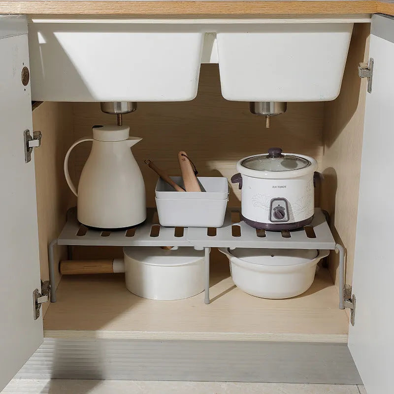 White telescopic kitchen storage rack at adjustable height on a countertop