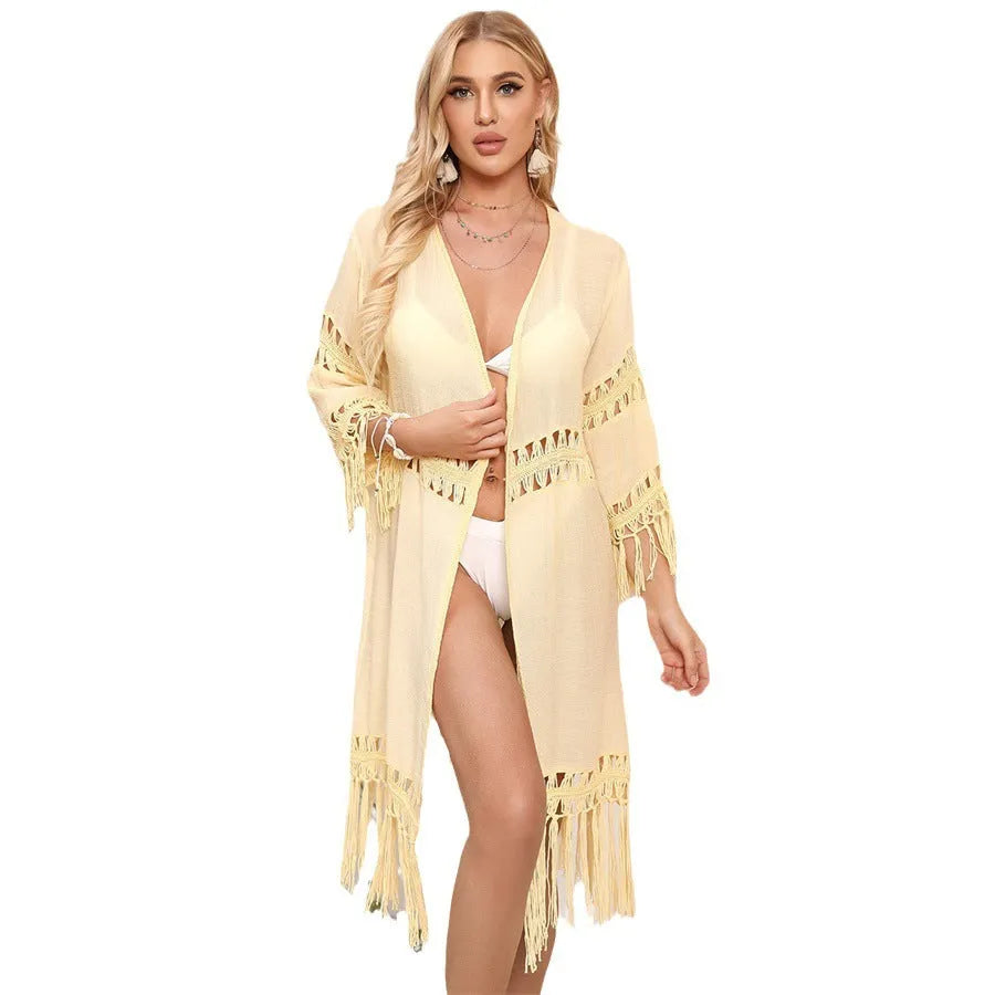 Yellow hand crocheted beach cover-up cardigan with tassel stitching on a mannequin