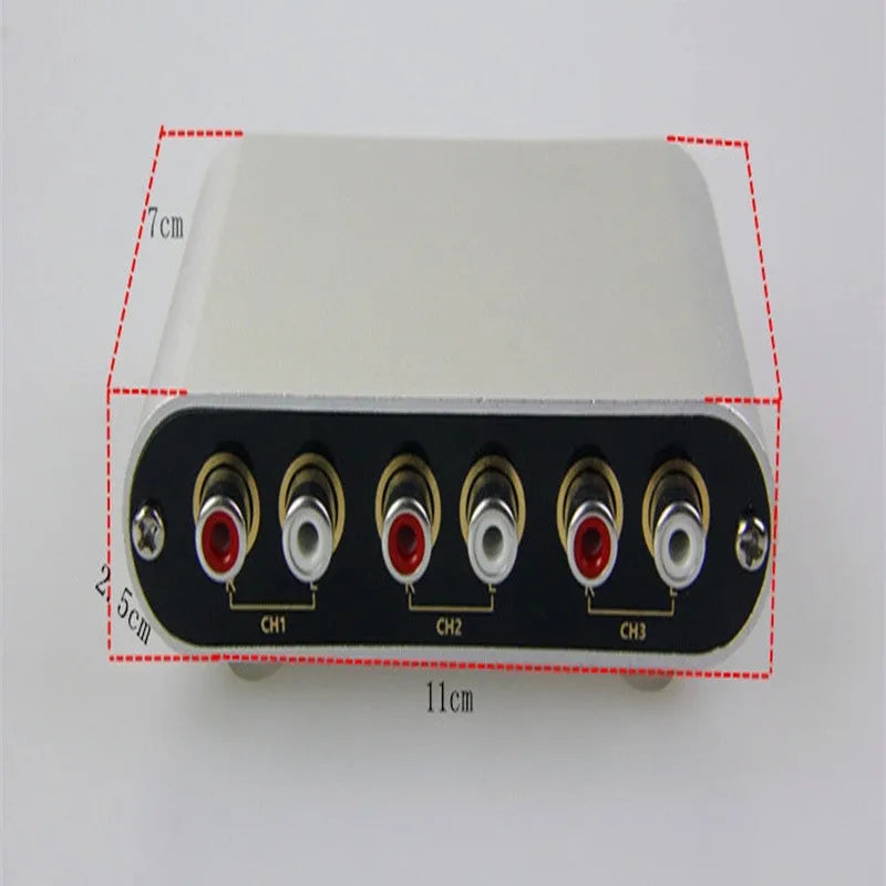 Silver aluminium audio source switch selector unit with infrared remote control on a black surface.