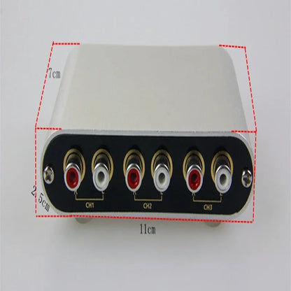 Silver aluminium audio source switch selector unit with infrared remote control on a black surface.