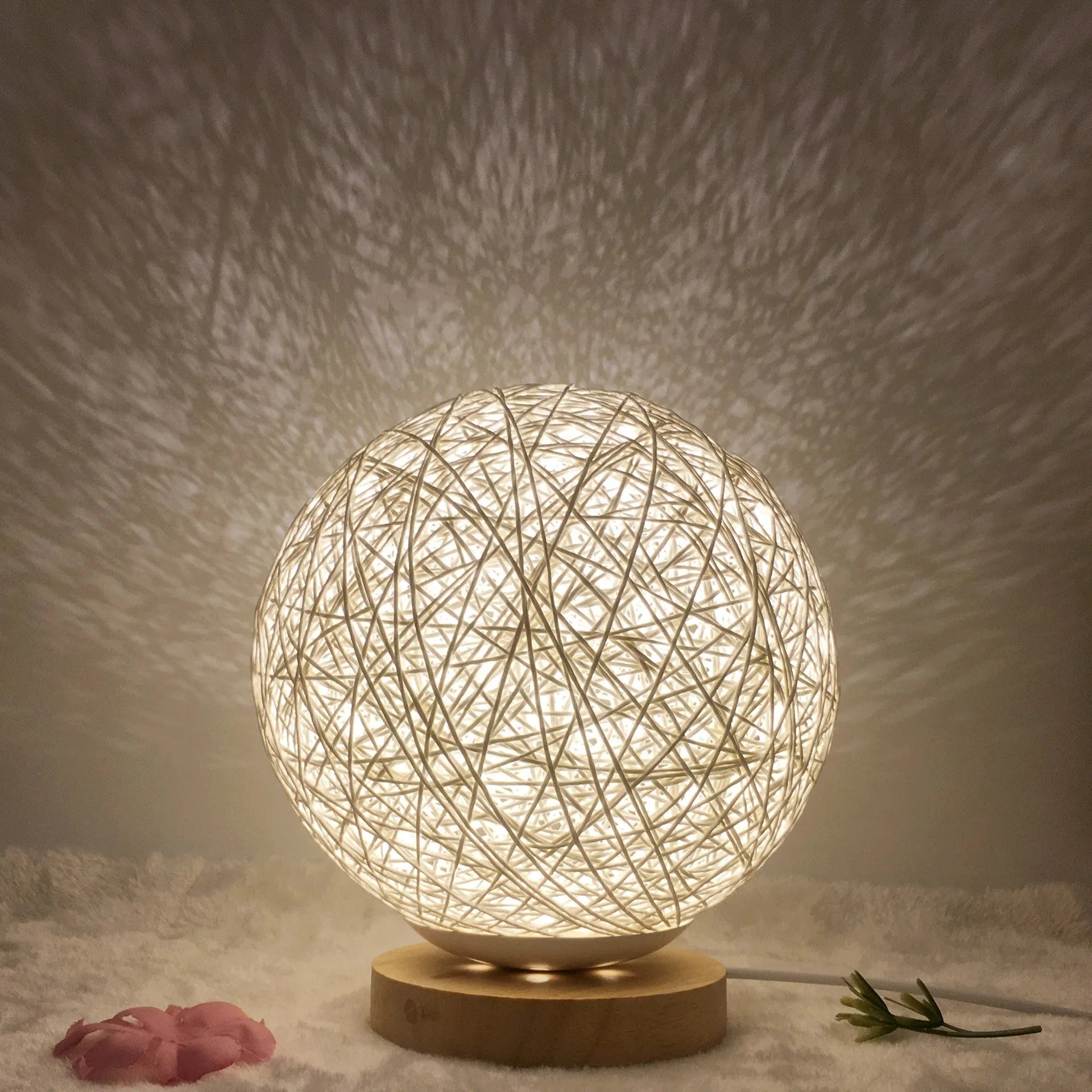 Spherical hand-knitted rattan table lamp with remote control on a wooden desk