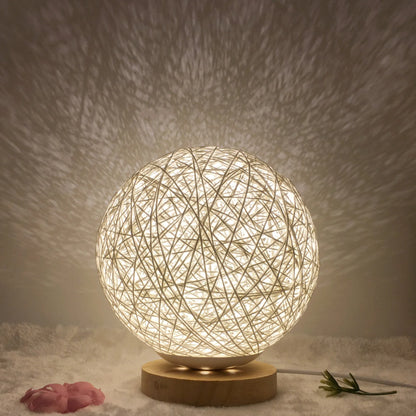 Spherical hand-knitted rattan table lamp with remote control on a wooden desk