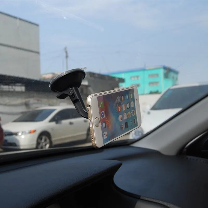 Classic black magnetic car phone holder mounted on a car dashboard, showing a smartphone attached.