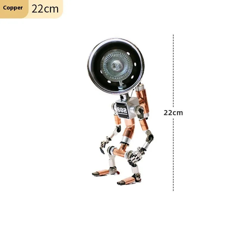 Silver metallic robot-shaped decorative desk lamp with internal LED glow on a wooden surface.