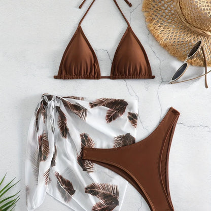 Women's orange three-piece bikini swimsuit with a matching printed gauze skirt laid flat.