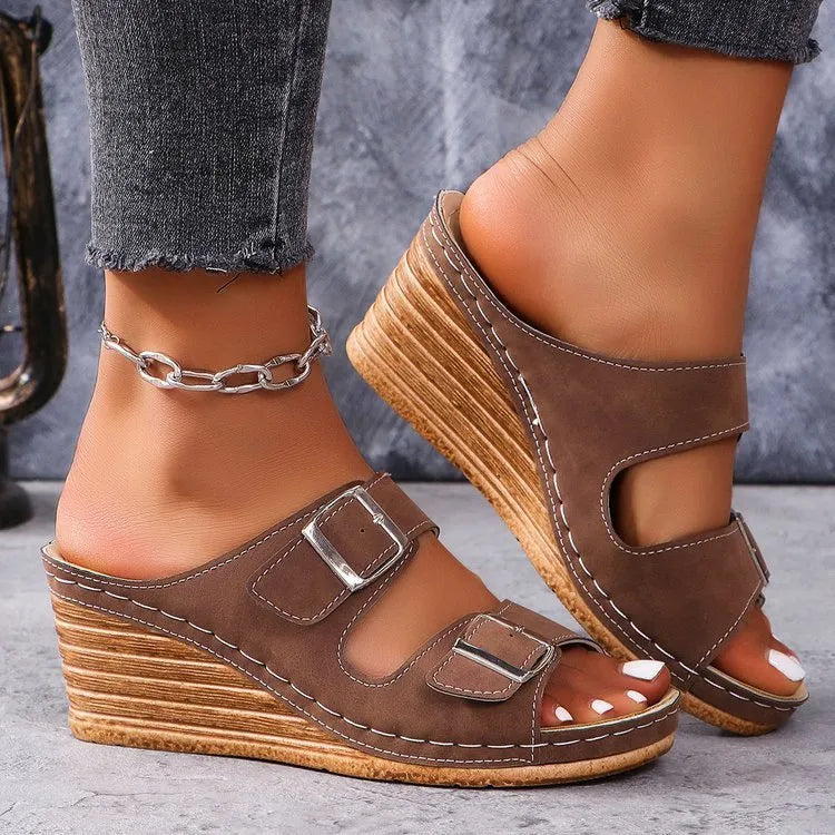 Women's creamy-white wedge slippers with an outer belt buckle and a rubber sole.