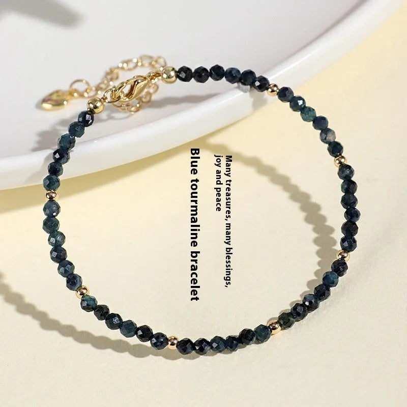 Close-up of a blue tourmaline beaded bracelet with 3mm stones and spacer beads on a wrist.