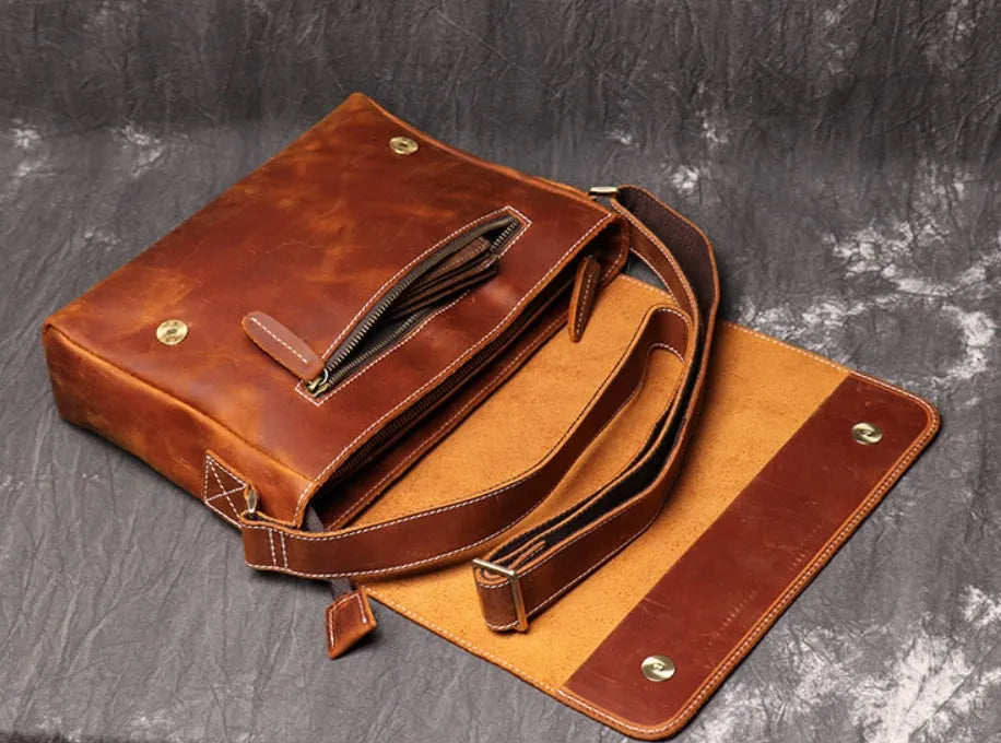 Vintage brown leather mens messenger bag with flap open, showing internal phone pouch and zipper pocket.