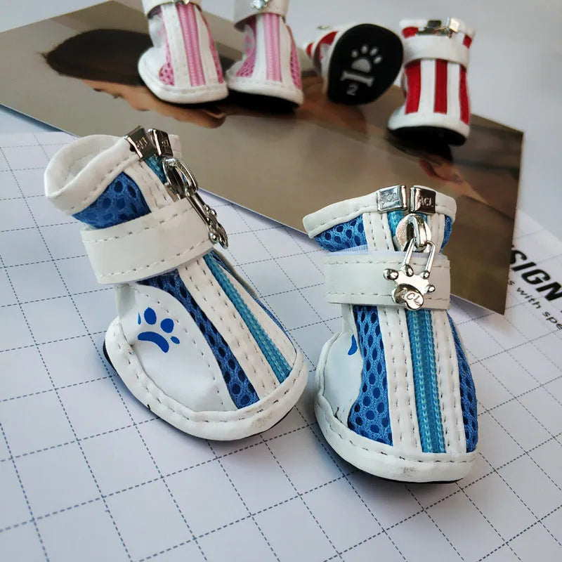 Four blue cloth dog shoes with zippers and non-slip soles laid out for a small dog.