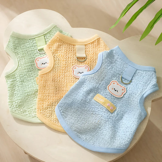 Green knitted cat clothing with a cartoon bear patch, showing hollowed-out breathable design.