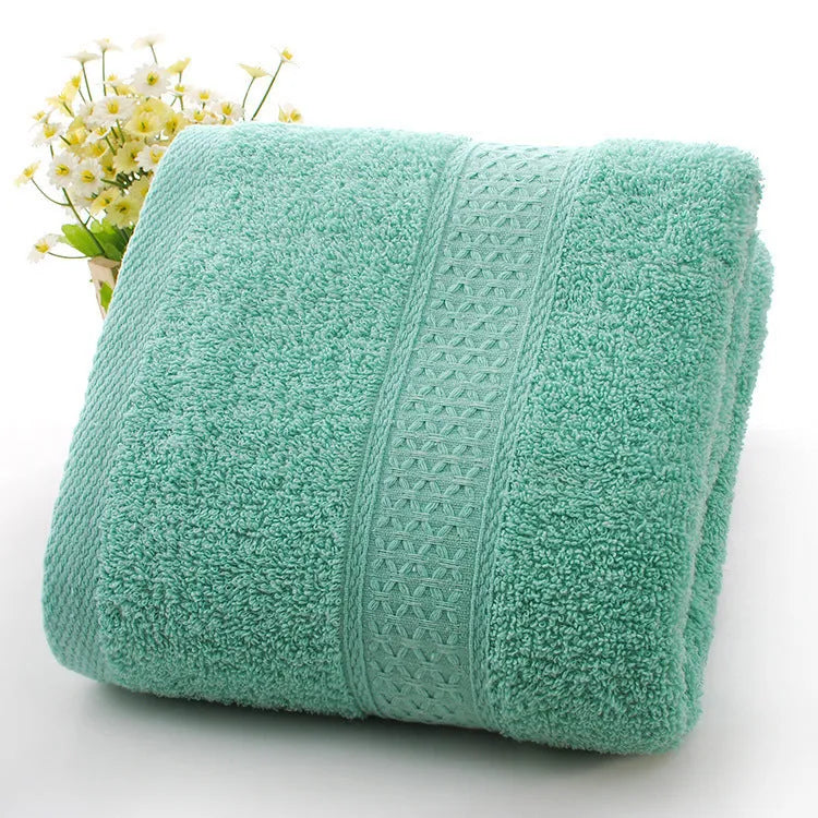 A stack of thickened cotton bath and beach towels in various colours including apple green, dark blue, and light pink.