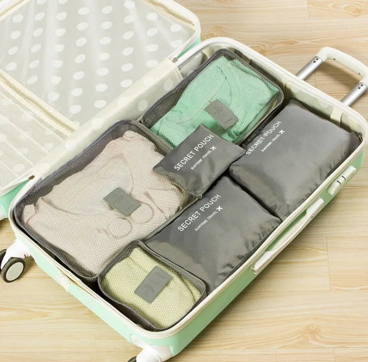Set of six coloured nylon packing cubes and flat pouches for travel organisation.