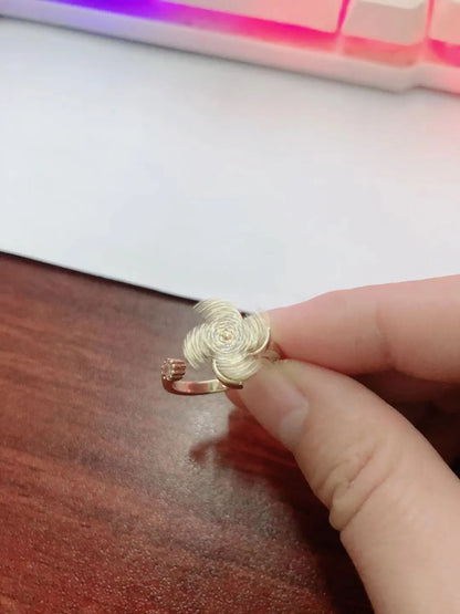 Gold rotating ring with a spinning geometric windmill design on a person's finger