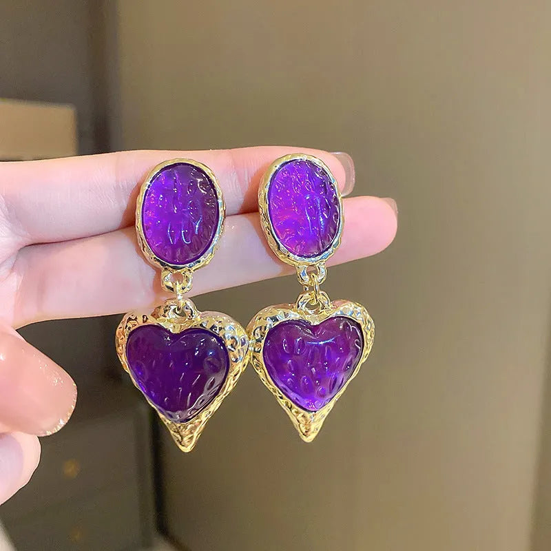 A pair of silver-tone stud earrings with a textured pleated oval love heart shape in various colour options.