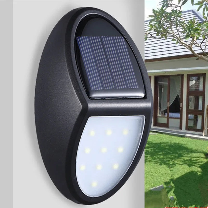 Black rectangular LED solar wall light mounted on an outdoor wall with a visible solar panel.