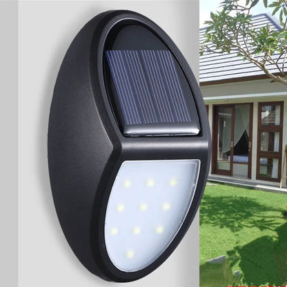 Black rectangular LED solar wall light mounted on an outdoor wall with a visible solar panel.