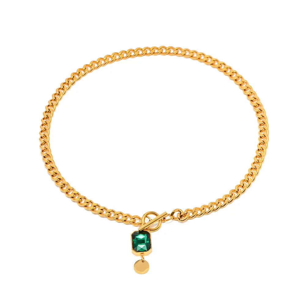 Gold tone geometric pendant necklace with emerald zircon stone on a Cuban link chain.