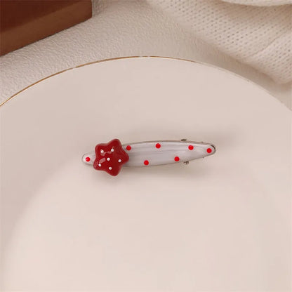 Red plastic hair clip with a 3D love heart and dots on a willow leaf-shaped base.