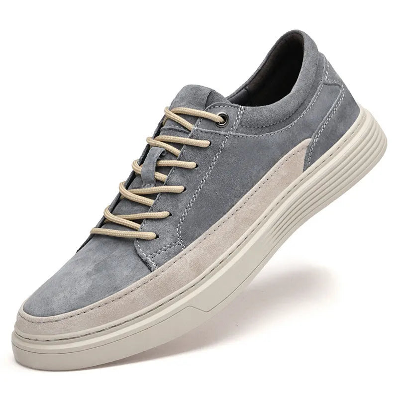 Men's grey low-top casual leather skate shoes with round toe and flat rubber sole on a wooden surface.