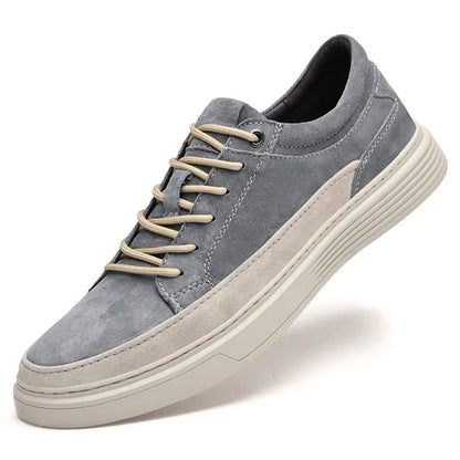 Men's grey low-top casual leather skate shoes with round toe and flat rubber sole on a wooden surface.