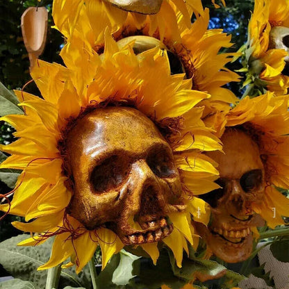 A group of skull-shaped sunflower ornaments arranged in a Halloween-themed outdoor display