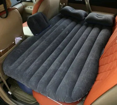 Black inflatable car bed with flocked surface and two pillows, shown folded into a chair inside a vehicle.